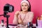 Image of adorable young woman tests some beauty products and shows lip gloss to her followers in blog. Beauty vlogger sits in
