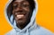 Image of african american guy wearing hood smiling and looking at camera