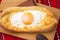 An image of an Ajarian khachapuri on table with raw egg close up