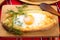 An image of an Ajarian khachapuri on table with raw egg close up