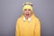 Image of annoyed irritated angry man wearing yellow hoodie, beanie hat headphones standing isolated over gray background,