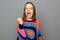 Image of attractive joyful woman wearing colorful sweater posing isolated over gray background, clenched fist, screaming yes,