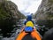 Image from back of female tourist with paddle canoe floating along river