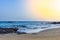 Image of a beach with a sailboat crossing the horizon