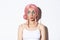 Image of beautiful silly girl in pink wig, with bright makeup, pouting and looking interested left, standing over white