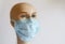 Image of a blue mask on the face of a gypsum mannequin. covid-19 virus concept, on bright background