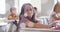 Image of bokeh light spots over happy biracial schoolgirl sitting at desk in class