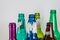 Image of the bottleneck of empty colored beer and wine glass bottles on a white background. Green, yellow, pink and blue