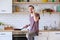 Image of brunet man with frying pan in his hands talking on phone in kitchen