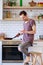 Image of brunet man with frying pan and phone in his hands in kitchen