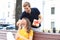 Image of charming excited couple in summer clothes smiling and holding present box together while sitting on bench