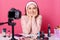 Image of charming young brunette woman advertises new beauty products, makes video her blog. Beauty vlogger sits smilling in front