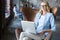 Image of cheerful office woman with blond hair in business wear sitting on chair and working with laptop office.