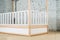 The image of the child's bed, in the frame of the bed legs and drawers. View of the railing of the crib