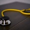 Image of close up with detail of yellow stethoscope on wooden background