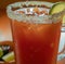 Image of close up of michelada drink in glass with sugar frosted edge and slice of lime