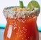 Image of close up of michelada drink in glass with sugar frosted edge and slice of lime