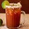 Image of close up of michelada drink in glass with sugar frosted edge and slice of lime