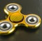 Image of close up of yellow metallic fidget spinner on grey background