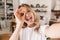 Image closeup of amusing blond woman looking at camera and taking selfie photo in living room