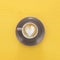 Image of coffe cup with foam of heart shape over wooden yellow background.
