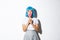 Image of coquettish asian girl in blue short wig, kissing heart-shaped candy, celebrating halloween, standing over white