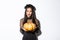 Image of cunning asian woman in black dress, impersonating evil witch on halloween, holding big pumpkin, standing over