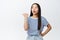 Image of curious asian woman pointing finger left and looking surprised, intrigued by something, showing advertisement