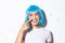 Image of cute and silly asian girl with confetti on her nose smiling and looking happy, wearing blue wig for halloween