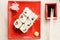 Image of delicious sushi wasabi and ginger on red plate with soy sauce and wooden chopsticks on white napkin background