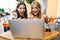 Image of delighted adult women holding credit card while using laptop