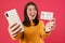 Image of delighted caucasian girl showing cellphone and credit card