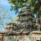 Image depicts a destroyed medieval Khmer building in Cambodia, visible amongst overgrown vegetation