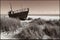 image of a deserted beach with an old boat broken fence around the dunes and clusters of sea oats.