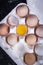 Image of egg yolk in a bowl next to healthy eggs in a dish or white  cloth and kitchen utensils.