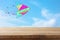 Image of empty rustic table in front of Colorful kite flying in the blue sky through the clouds. For product display presentation.