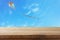 Image of empty rustic table in front of Colorful kite flying in the blue sky through the clouds. For product display presentation.