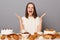 Image of excited joyful cheerful woman with brown hair sitting at table isolated over gray background, having lots delicious