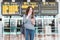 Image of excited, shocked young beautiful woman, standing in airport with smartphone in her hands