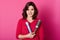 Image of female hairdresser holds comb and hairspay, wears red sweater, ready to make hairstyle her client, models over pink