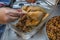 Image of female hands tying with string the legs of a raw and fresh whole chicken before being baked