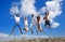 Image of five energetic people jumping at the beach