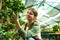 Image of florist girl 20s wearing apron working in greenhouse