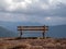 Image with focus of bench with mountains in the background