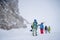 Image of four sports people with skis and snowboard walking in winter resort