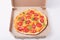 Image of fresh tasty pizza in cardboard box on white surface, picture of fast food dish, supper from restaurant or cafe. Fast food