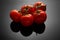 Image of fresh tomatoes bunch on black background with reflection and water drops