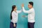 Image of friendly young people man and woman in basic clothing laughing and giving high five isolated over blue background