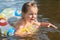 Image of frightened sweet little kid opening mouth and eyes widely with scare, swimming with rubber circle, screaming for help,