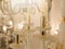 Image of a glowing lamp with white glass fittings and candlelight shades on a gold stand. The concept of the classical style in th